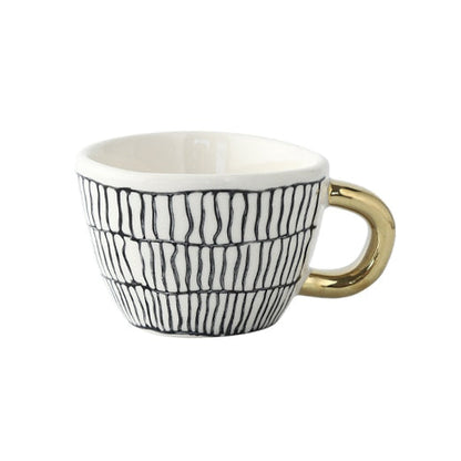 Tasse mit abstraktem geometrischem Muster und goldenem Henkel