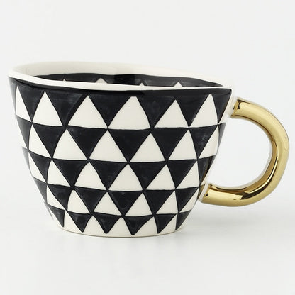 Tasse mit abstraktem geometrischem Muster und goldenem Henkel