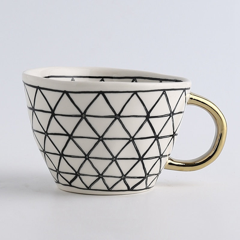 Tasse mit abstraktem geometrischem Muster und goldenem Henkel