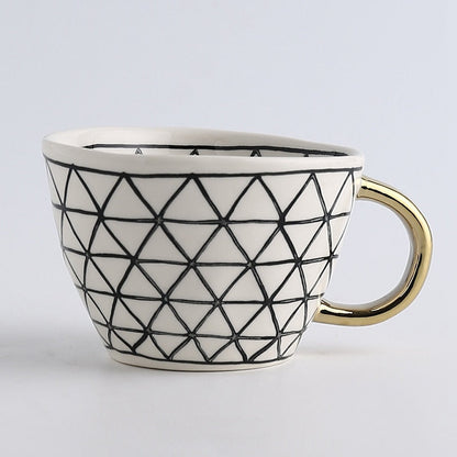 Tasse mit abstraktem geometrischem Muster und goldenem Henkel