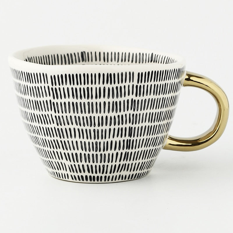 Tasse mit abstraktem geometrischem Muster und goldenem Henkel