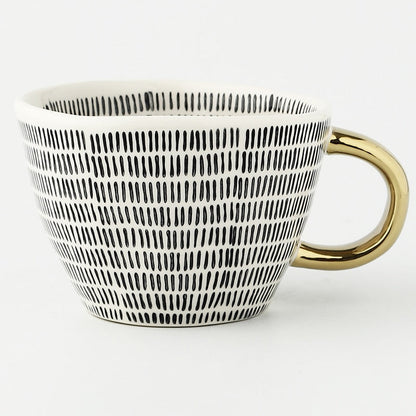 Tasse mit abstraktem geometrischem Muster und goldenem Henkel