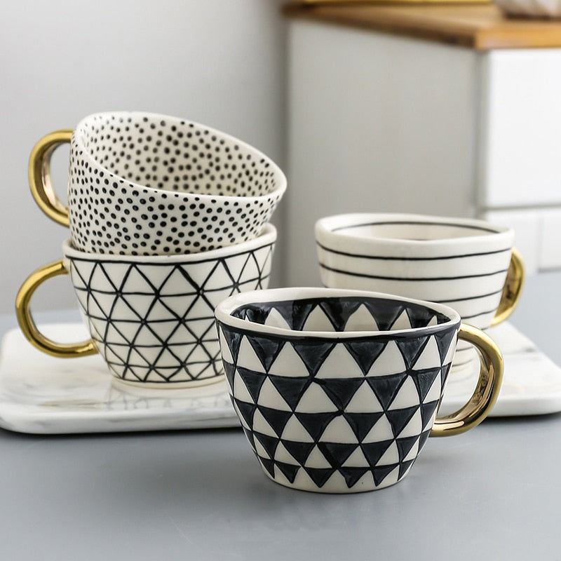 Tasse mit abstraktem geometrischem Muster und goldenem Henkel