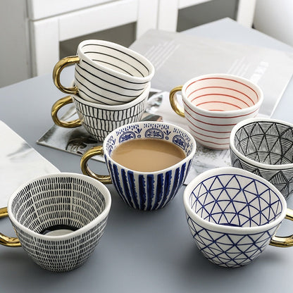 Tasse mit abstraktem geometrischem Muster und goldenem Henkel