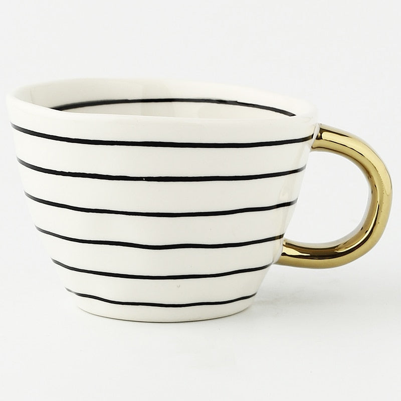 Tasse mit abstraktem geometrischem Muster und goldenem Henkel