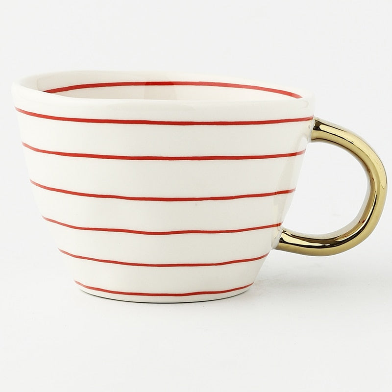 Tasse mit abstraktem geometrischem Muster und goldenem Henkel