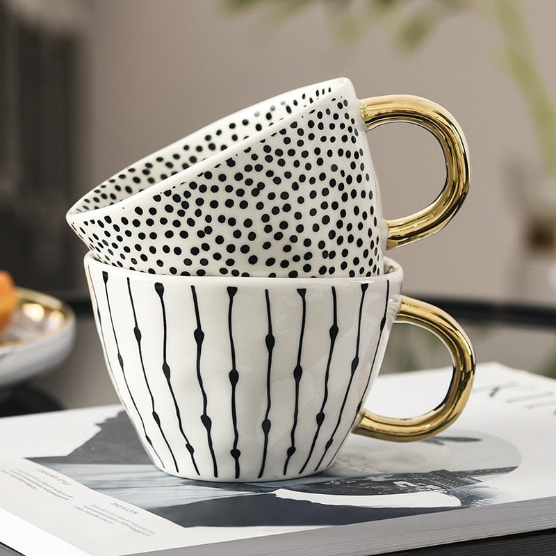 Tasse mit abstraktem geometrischem Muster und goldenem Henkel