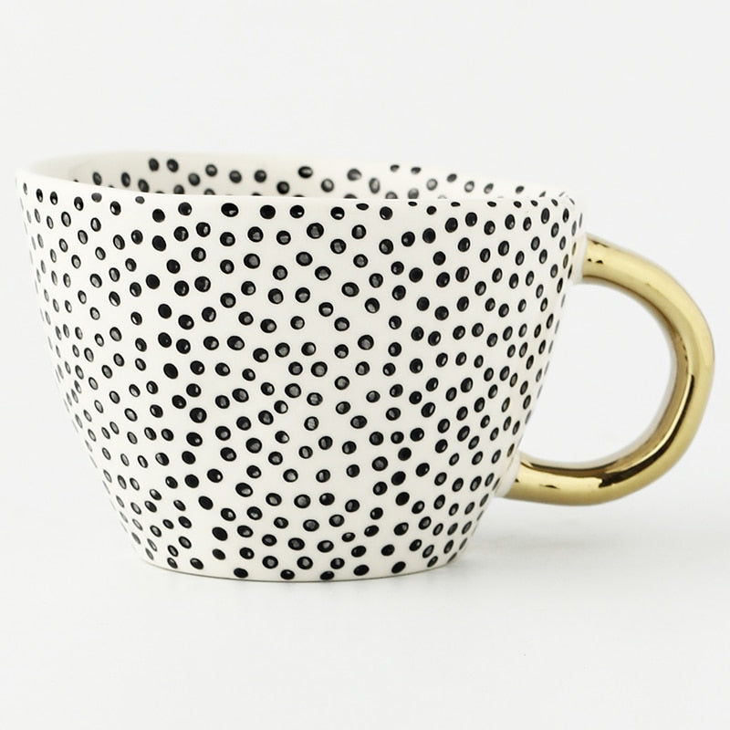 Tasse mit abstraktem geometrischem Muster und goldenem Henkel