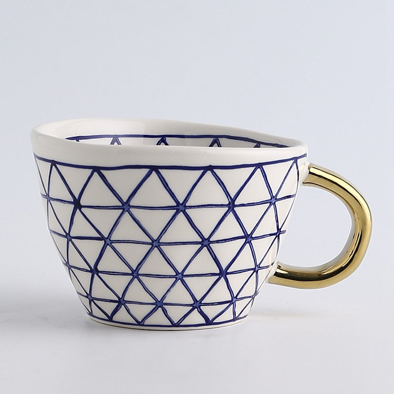 Tasse mit abstraktem geometrischem Muster und goldenem Henkel