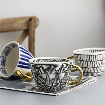 Tasse mit abstraktem geometrischem Muster und goldenem Henkel