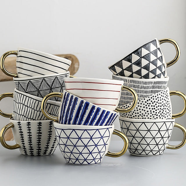 Tasse mit abstraktem geometrischem Muster und goldenem Henkel