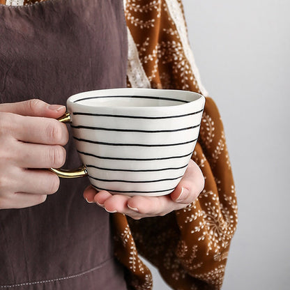 Tasse mit abstraktem geometrischem Muster und goldenem Henkel